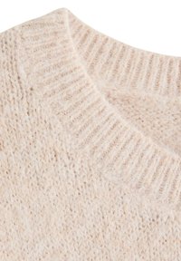 Nærbillede af en blød, beige strikket sweater, der viser ribbet rund halsudskæring og et fluffet tekstureret stof.