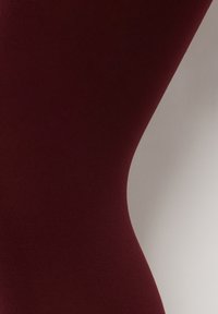 Burgundy sömlösa leggings med en slät textur, en åtsittande form och en subtil lyster, utformade för komfort och mångsidighet.