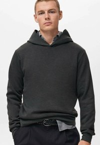 Donkergrijze hoodie met een ontspannen pasvorm, minimalistisch ontwerp, lange mouwen en een brede capuchon; gedragen over een overhemd met kraag en zwarte broek.