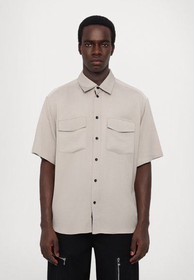 Short-sleeve, light gray button-up shirt with a collar, featuring two chest pockets and black buttons. Smooth fabric with a tailored fit.