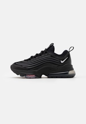 Baskets Nike Air Zoom noires avec des bandes réfléchissantes ondulées, un amorti à air visible dans la semelle et un logo Nike swoosh blanc sur le côté.