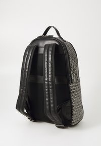 Crna kožna ruksak s geometrijskim uzorkom od tkanine, podstavljene podesive naramenice i ručkom na vrhu za nošenje.