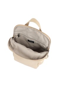 Zaino beige con una superficie liscia, dotato di un compartimento principale con zip e di una tasca interna, con una maniglia in tessuto sulla parte superiore.