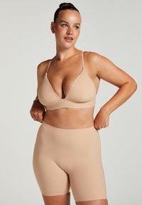 Nude naadloze bh en mid-rise shorts, beide gemaakt van zachte, elastische stof. De bh heeft een lage V-halslijn en verstelbare bandjes.