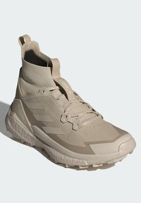 Bežiniai sportiniai batai su aukšta apykakle, tekstūruotų audinių viršus, sustiprinta pirštų dalis ir neslystantis padas. Įrengti raišteliai ir traukimo kilpa, skirta lengvam užsivilkimui.