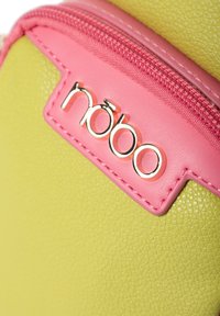 Materiale in pelle verde testurizzato con una cerniera rosa e un'etichetta rettangolare rosa che mostra il nome del marchio "nobo" in caratteri dorati.