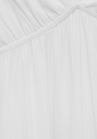Gros plan sur un tissu blanc avec de fines plis verticaux et une couture diagonale avec des fronces.