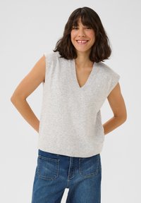 Haut sans manches en maille gris clair avec un col en V, présentant une coupe légèrement ample et un ourlet côtelé, porté avec un jean en denim bleu.