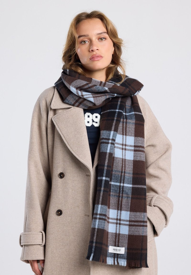 Karierter Schal in Braun, Blau und Weiß, aus weichem Stoff, um den Hals gewickelt, kombiniert mit einem beigen Wollmantel.