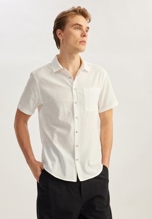 Korte mouwen, witte button-up shirt gemaakt van lichte stof. Bevat een borstzak en bruine knopen, met een ontspannen pasvorm.