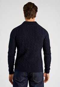 Marineblauer Pullover mit Kabelstrickmuster, Rippkragen und Bündchen, mit strukturiertem Muster. Rückansicht zeigt ein tailliertes Design und einen geraden Saum.