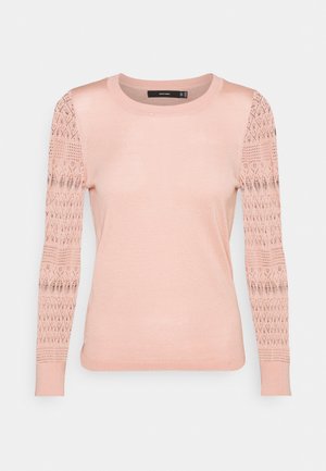 Haut en maille rose clair à manches longues avec col rond et manches transparentes à motif dentelle, corps ajusté et poignets côtelés.