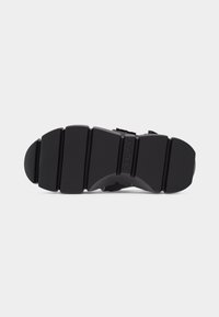 Μαύρη τμηματική σόλα αθλητικού παπουτσιού με βαθιές αυλακώσεις και το όνομα της μάρκας "REPLAY" ανάγλυφο στο κέντρο.