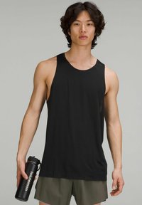 Débardeur noir à col rond et emmanchures, associé à un short vert olive. Le modèle tient une bouteille d'eau noire étiquetée "lululemon."