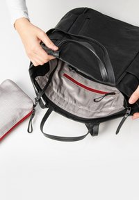 Schwarze Stoff-Schultertasche mit Lederakzenten, ausgestattet mit einem grauen Innenraum, einer roten Reißverschlusstasche und einem abnehmbaren grauen Beutel mit Karomuster.