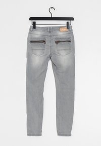 Grå jeans med slim fit, som har två bakfickor, var och en med dragkedjor och subtila urblekta ytor på tyget.