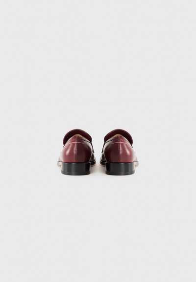 Burgundy läderskor med låg klack, rund tå och sidoutskärningar. Har sömnadsdetaljer och slät yta.