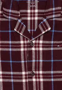 Bordeauxfarbenes Flanellhemd mit blau-weißer Karomuster, spitzem Kragen, Knopfverschluss und Tommy Hilfiger Logo-Akzent auf der Brust.
