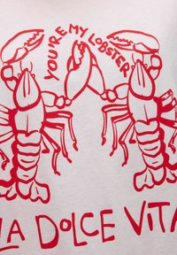 La tela blanca presenta ilustraciones gráficas rojas de langostas con el texto "ERES MI LANGOSTA" y "LA DOLCE VITA" debajo.