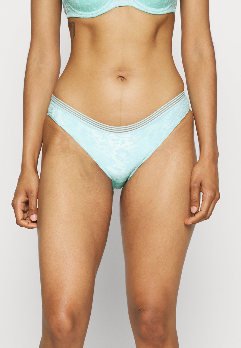 Parte de baixo de bikini azul claro com padrão de renda floral, apresentando uma textura suave e uma cintura fina com listras contrastantes.