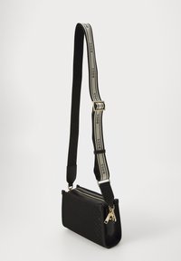 Borsa a spalla in pelle nera con una forma strutturata, accessori in oro e design a motivo. Presenta una tracolla larga e regolabile con accenti del logo.