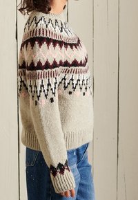 Neulepaita vaaleanharmaana, jossa on pyöreä kaula-aukko, ja jossa on kuvioitu yläosa viininpunaisena, mustana ja vaaleanpunaisena. Ribbaus hihansuissa ja helman päällä.