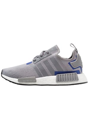 Jasnoszare sportowe buty z siateczkową cholewką, trzema ciemniejszymi szarymi paskami po boku, białą amortyzującą podeszwą i niebieskimi akcentami.