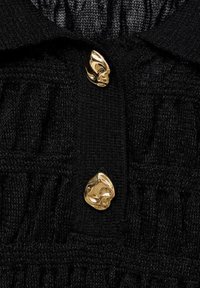 Pull en tricot noir avec un motif texturé et un col, agrémenté de deux boutons dorés brillants en accent métallique.