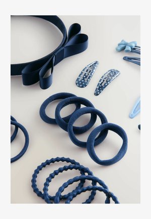 Mariene haaraccessoires gerangschikt op een lichte ondergrond: een haarband, elastiekjes en clips met verschillende texturen en patronen.