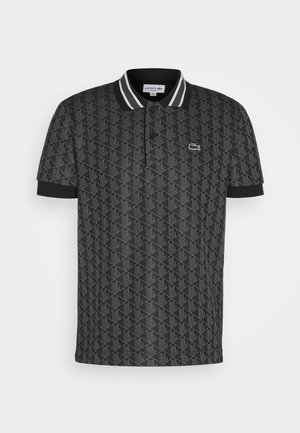 Camisa polo negra con un patrón geométrico, tapeta de dos botones y rayas en el cuello en contraste. Presenta un pequeño logo verde de Lacoste.