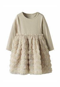 Cremefarbenes Langarmkleid mit einem gerippten Oberteil und einem Rüschenschnüffelrock, geschmückt mit Stoffrosenapplikationen, die ein strukturiertes Aussehen erzeugen.