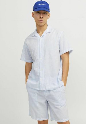Camicetta a maniche corte, con bottoni, e pantaloni corti abbinati, entrambi in tessuto a scacchi blu chiaro, con vestibilità rilassata e superficie texture. Cappello blu.