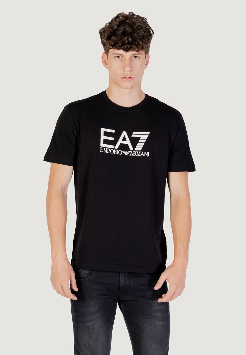 Camiseta de algodón negra con un logo gráfico blanco "EA7 EMPORIO ARMANI" en el frente. Mangas cortas, cuello redondo y dobladillo recto.