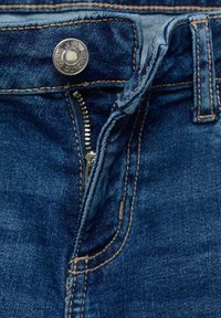 Jeans iz denima z temno modrim pranjem, z uporabo srebrnega kovinskega gumbka, zadrge in rjavimi šivi ob pasu ter žepih.