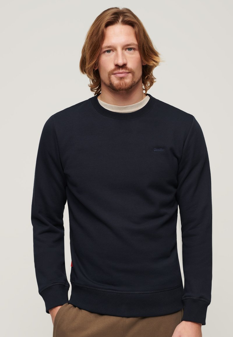 Felpa crewneck navy in morbido cotone, con polsini e orlo a costine, e un piccolo logo sul petto.