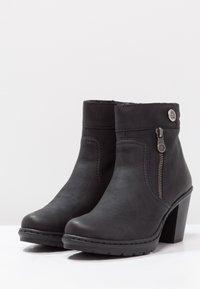 Czarne skórzane botki za kostkę z grubym obcasem, bocznym zamkiem błyskawicznym i przeszyciami. Gładkie wykończenie z teksturowanym górnym brzegiem.