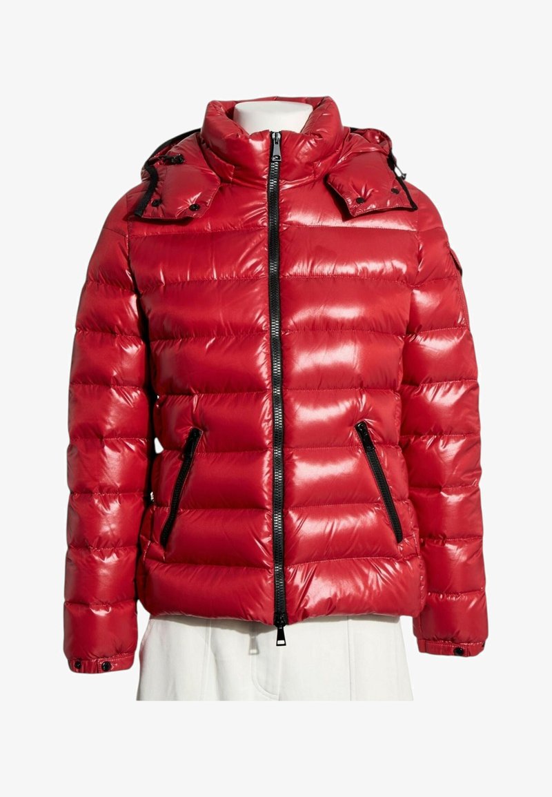 Doudoune rouge brillante avec fermeture éclair noire et poches zippées, col montant et poignets boutonnés sur un torse de mannequin blanc.