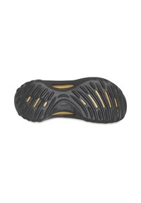 Semelle de chaussure en caoutchouc noir avec un motif texturé et des rainures, dotée d'accents jaunes et de trous de drainage pour améliorer l'adhérence et la flexibilité.