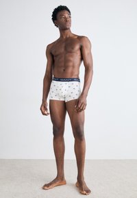 Hvit boxerbriefs med mønster av små, fargerike figurer. Elastisk linning i marineblått med "GANT"-logo. Myk og elastisk stoff.