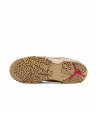 Shoe sole features a textured beige rubber base with circular and star-shaped patterns; red Jumpman logo near the heel.
