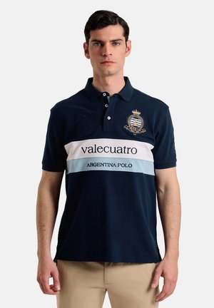 Camisa polo de color azul marino con una franja horizontal blanca y azul claro, con logotipo bordado, número "2" y cuello.