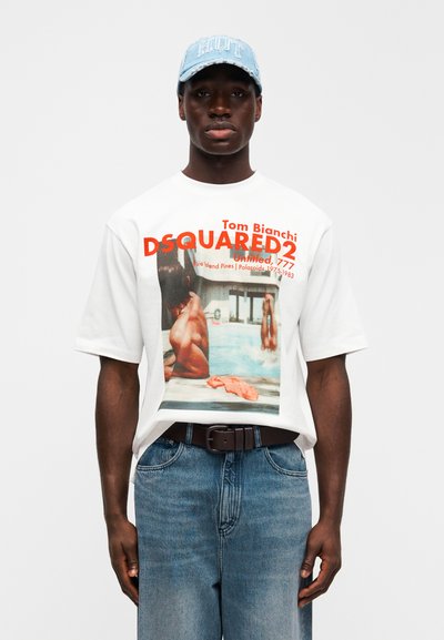 Λευκό κοντομάνικο μπλουζάκι με μεγάλο έγχρωμο φωτογραφικό τύπωμα, πορτοκαλί κείμενο και σκούρο μπλε τζιν σορτς. Ανοιχτό μπλε καπέλο με κεντημένο το «Riot».