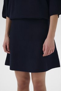 Tumesinist värvi kootud kampsun ja sobiv seelik. Kampsunil on lõdvestunud lõige, seelikul on lehviva äärega tekstuuriga kangas.