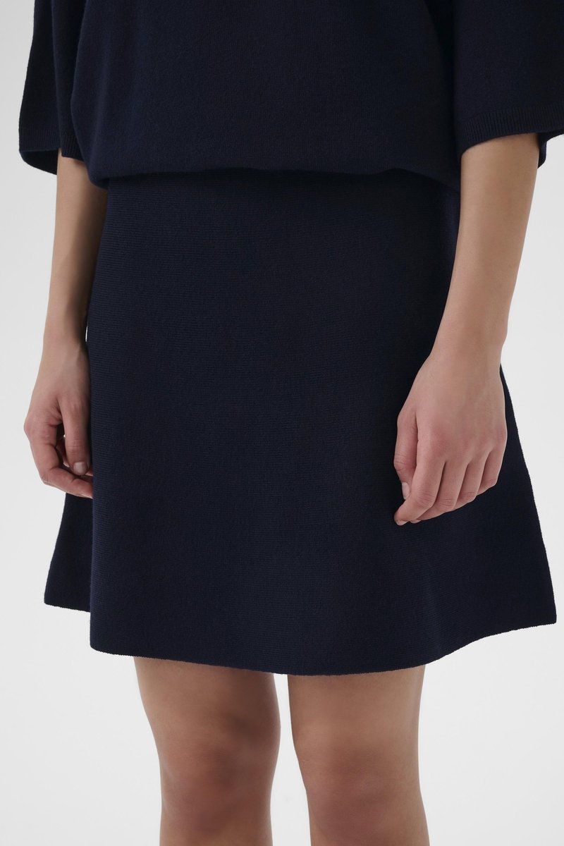 Pull tricot bleu marine et jupe assortie. Le pull présente une coupe ample, tandis que la jupe a un ourlet évasé et un tissu texturé.