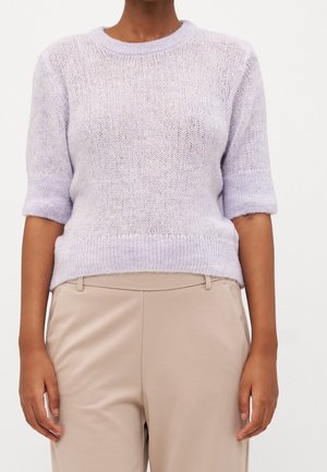 Lila kortärmad stickad tröja med rund halsringning och något ribbad nederkant. Bar över beige byxor som har ett lätt, texturerat tyg.