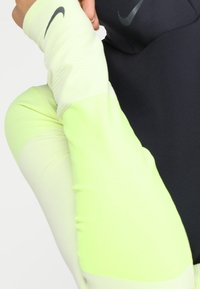 Długo rękawowy, sportowy top z czarnym korpusem i jasnoniebiesko-zielonymi rękawami, wykonany z lekkiego, odprowadzającego wilgoć materiału.