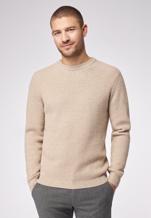 Beżowy sweter z prążkowanego dzianiny, z okrągłym dekoltem i długimi rękawami. Materiał jest miękki, a krój dopasowany z lekko zaokrąglonym dołem.