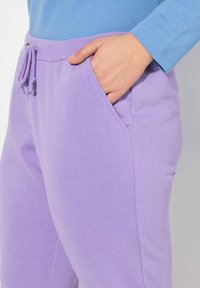 Lavendel joggingbyxor med ribbad midja och snörning. Har sidofickor. Slät textur, avslappnad passform och sydda detaljer.