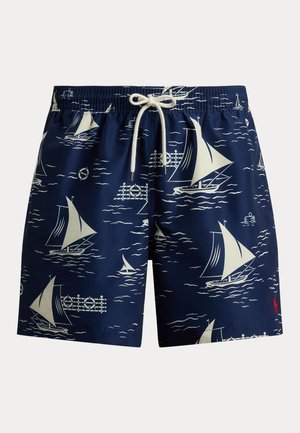 Tengerészkék fürdőnadrág fehér vitorlás és óceáni hullám mintákkal, elasztikus derékrésszel, fehér zsinórral és piros logóval a szegély közelében.