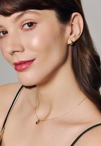 Złote kolczyki w kształcie kropel oraz pasujący naszyjnik z małym wisiorkiem. Biżuteria ma polerowane wykończenie i delikatny wzór łańcuszka.